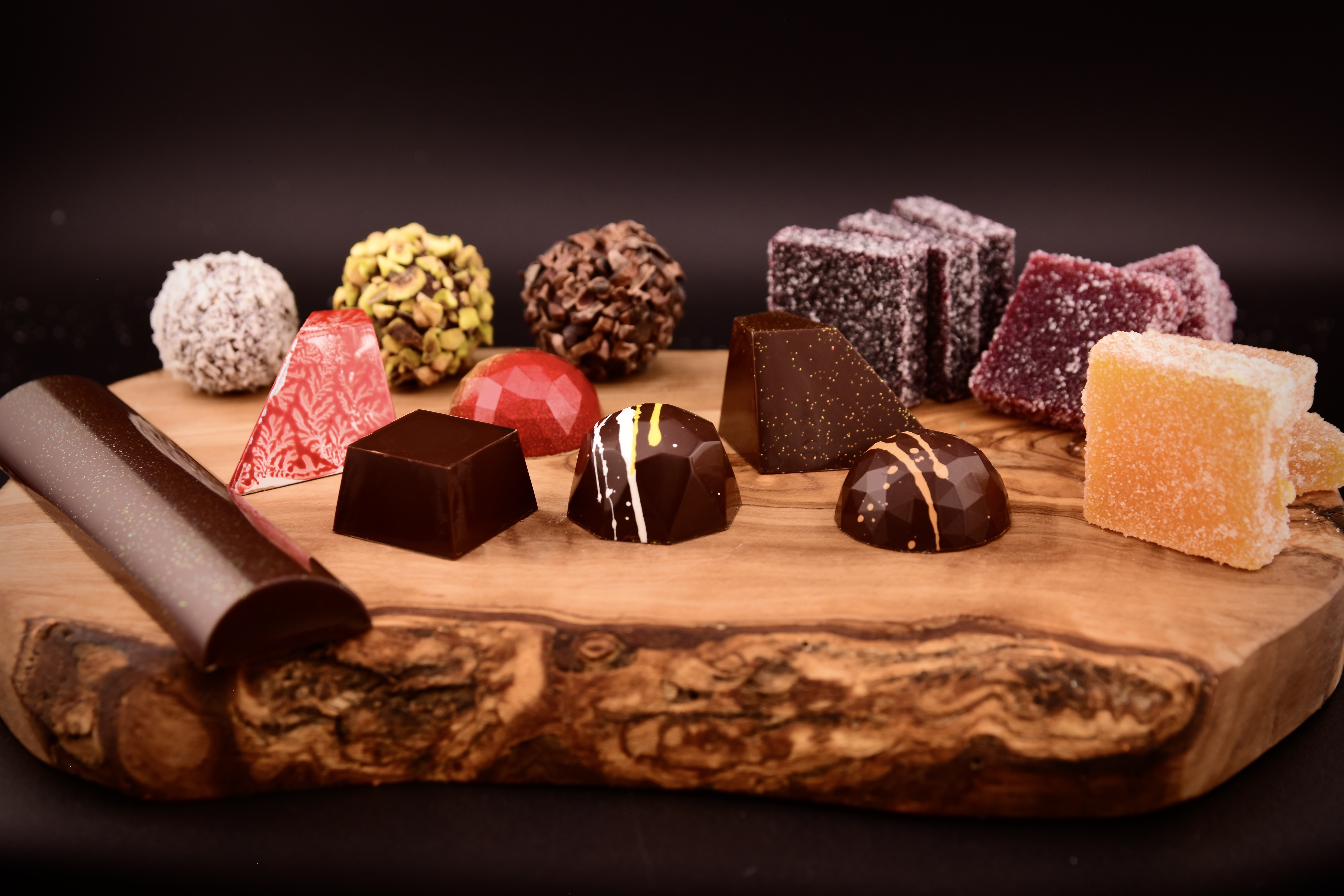 Actual Alpen bonbons, truffles, and colorful pâte de fruit on a wooden board